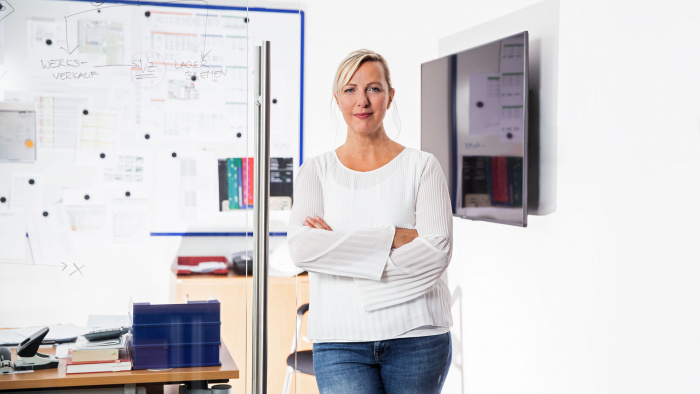 Junge Frau steht vor Büro mit verschränkten Armen 