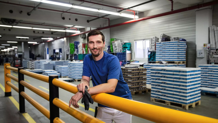 Mitarbeiter Logistik lehnt im Lager an einer Brüstung