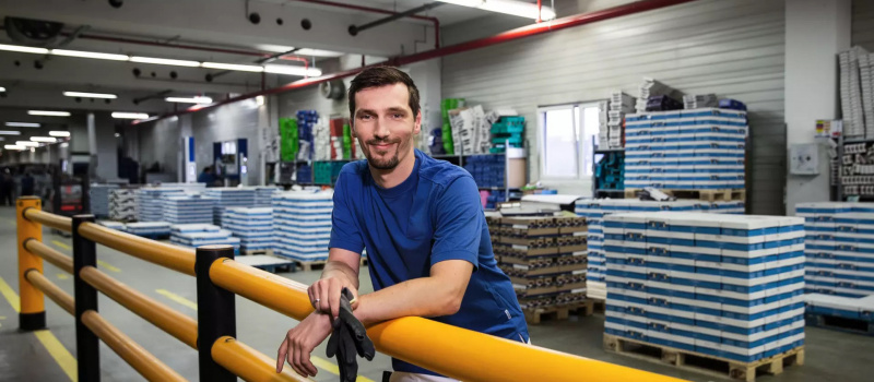 Mitarbeiter Logistik lehnt im Lager an einer Brüstung